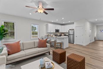 a living room with a couch a table and chairs and a kitchen in the background
